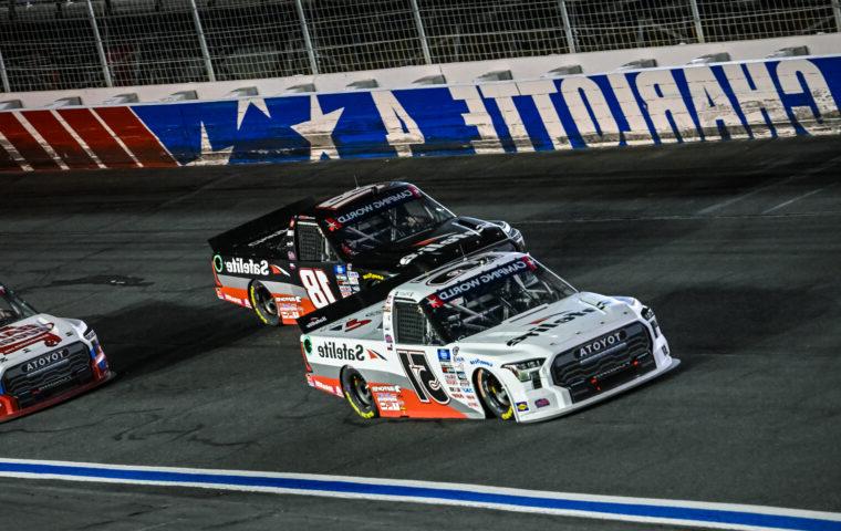 three race trucks driving on speedway